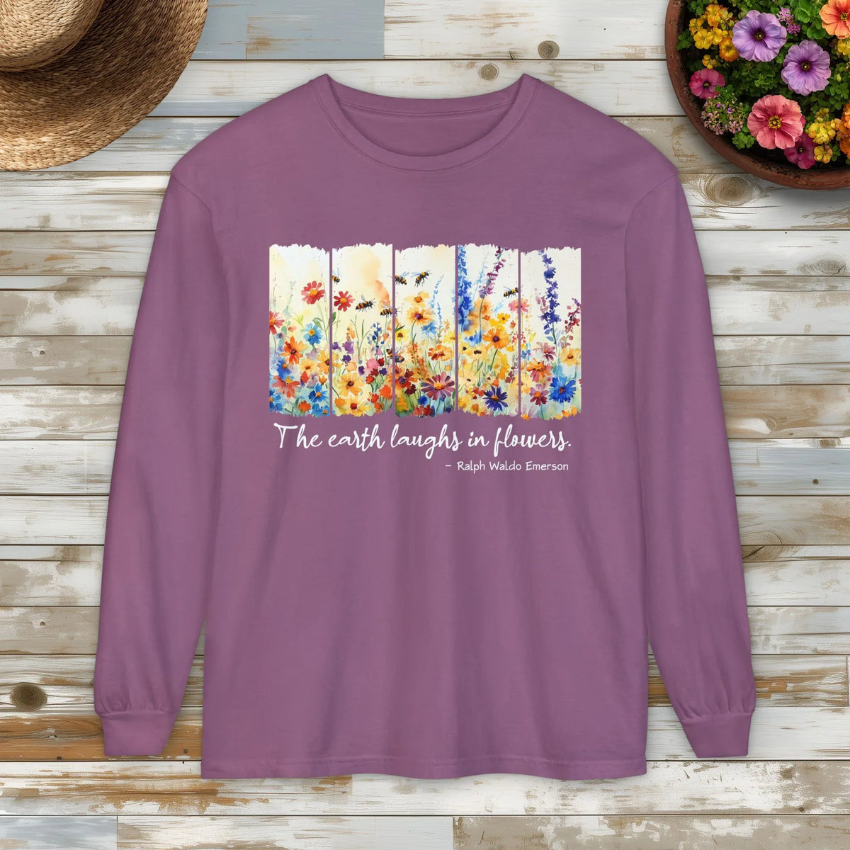 Purple long-sleeve shirt with floral design and quote on a wooden surface.