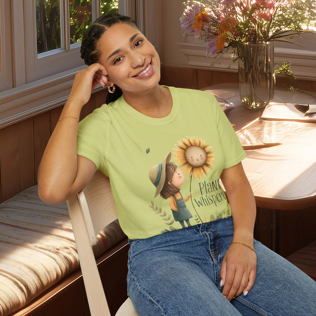 Woman wearing a green t-shirt with a sunflower design and text, sitting in a bright room.