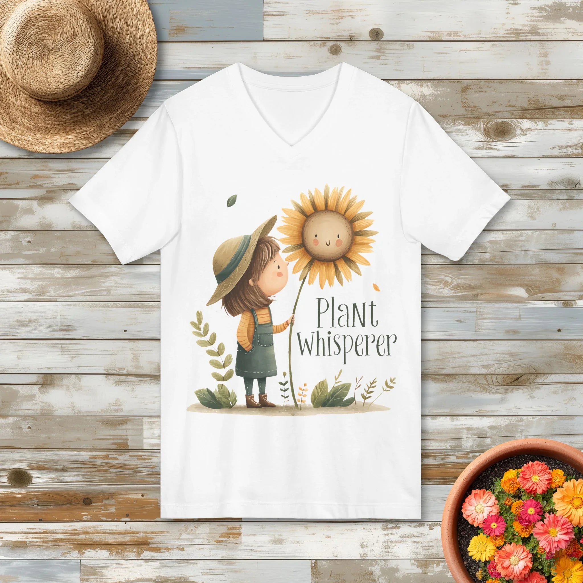 White t-shirt with a cottagecore girl holding a sunflower and 'Plant Whisperer' text on a wooden surface.